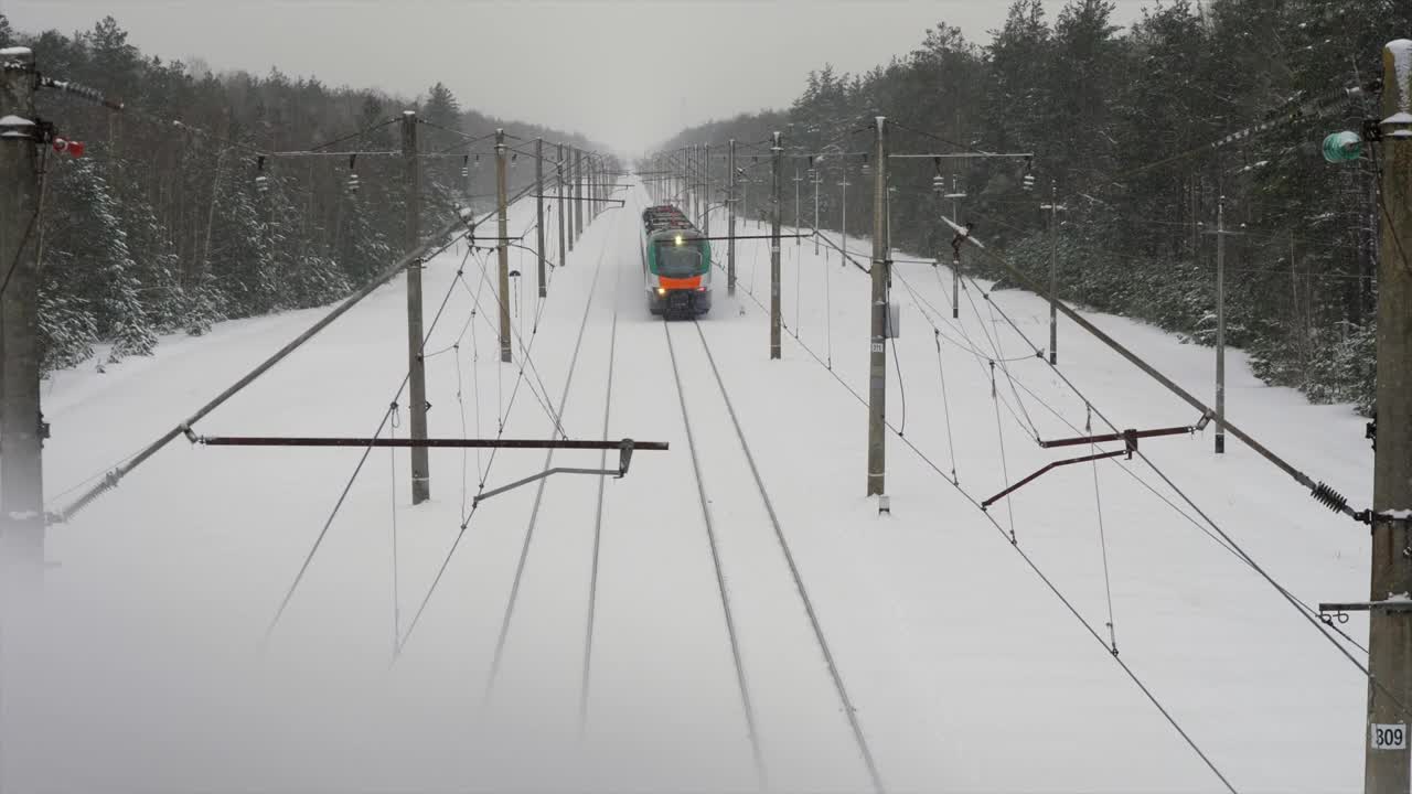 城际现代电动火车行驶在积雪覆盖的铁轨上视频素材