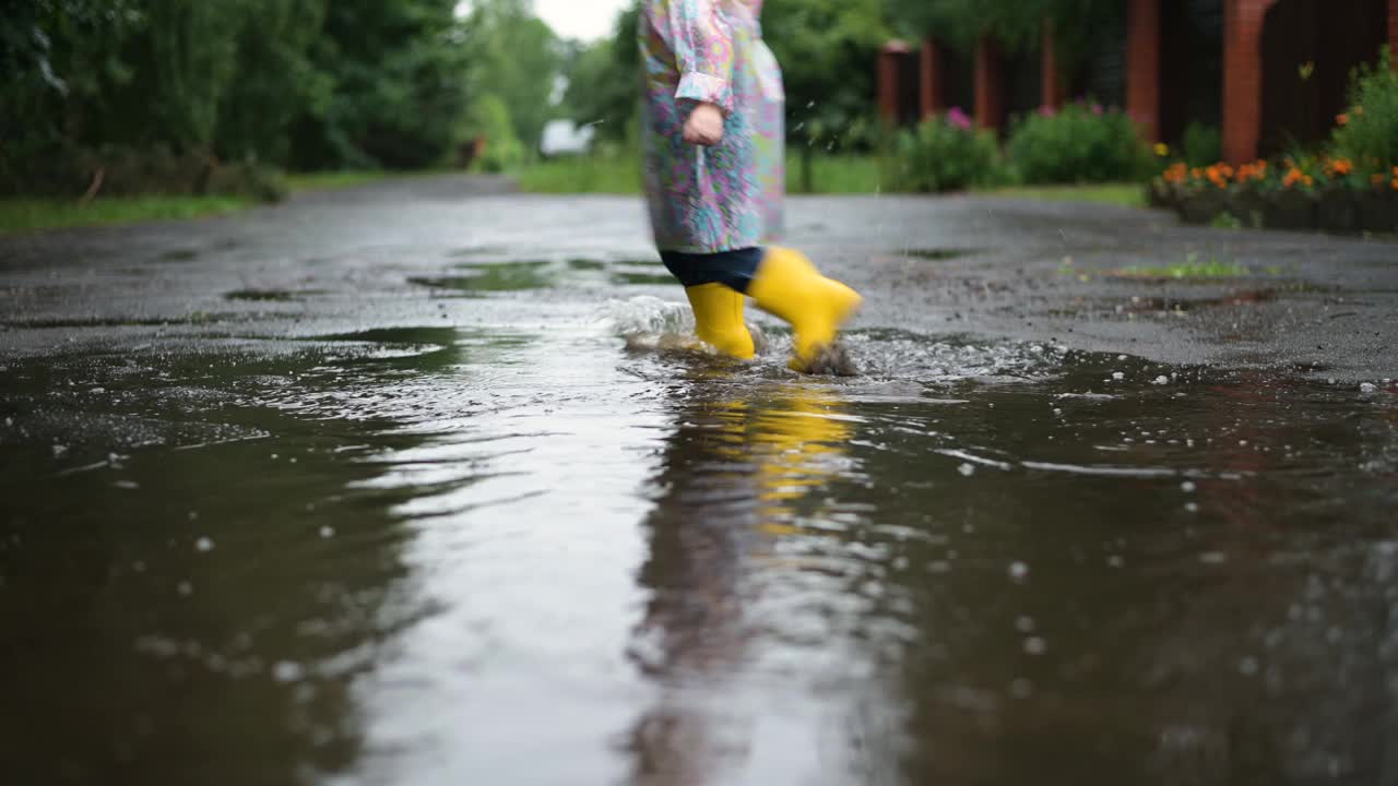 下雨天，孩子们的黄色胶靴踩在水坑上视频素材