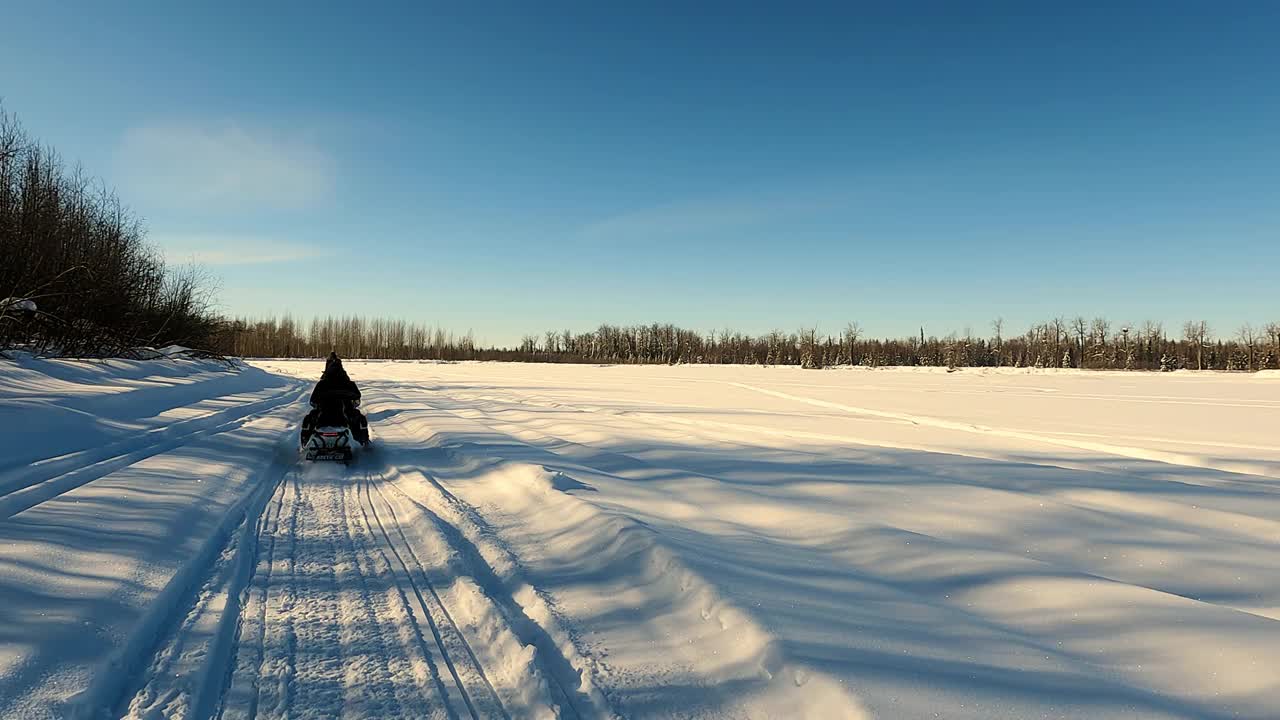 两辆雪地车通过松林的慢镜头POV视图视频素材