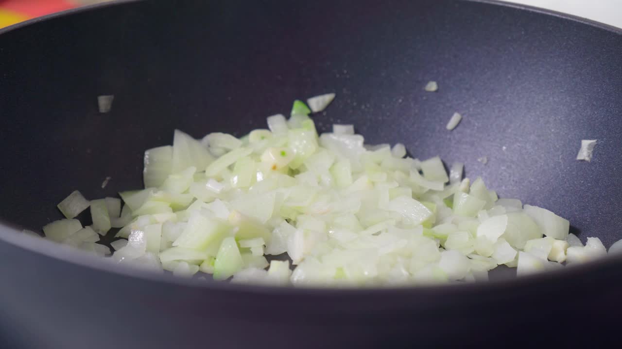 近距离观察煎锅里的炒洋葱。准备晚餐。在家做饭的概念。有选择性的重点。视频素材