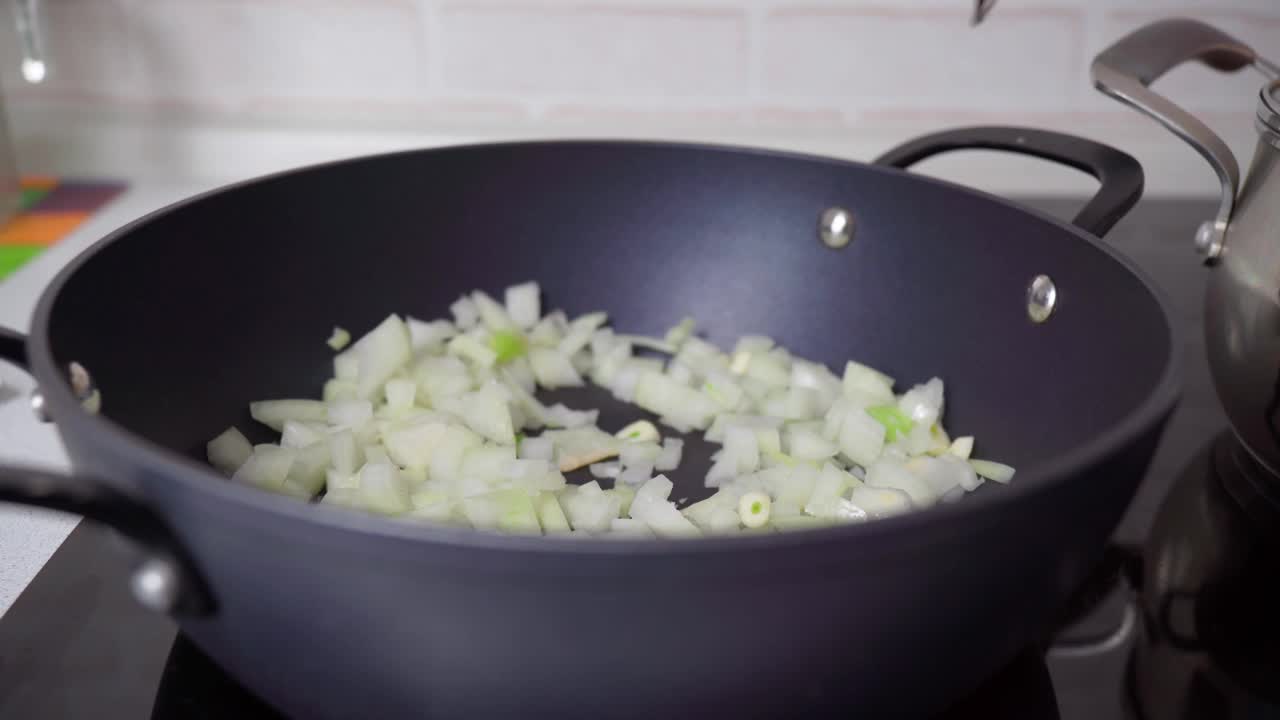 煎锅里的洋葱。准备晚餐。在家做饭的概念。有选择性的重点。视频素材