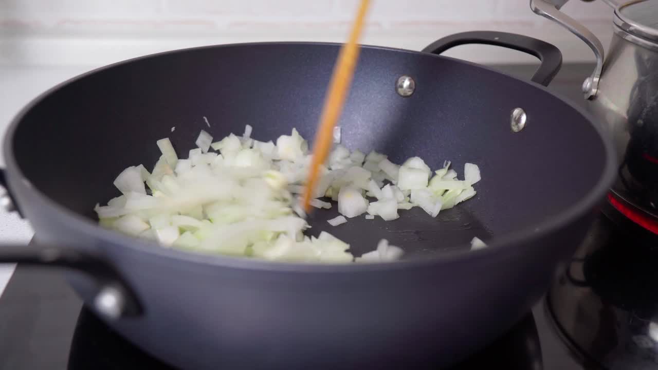 在煎锅里切洋葱。对烹饪原料。有选择性的重点视频素材