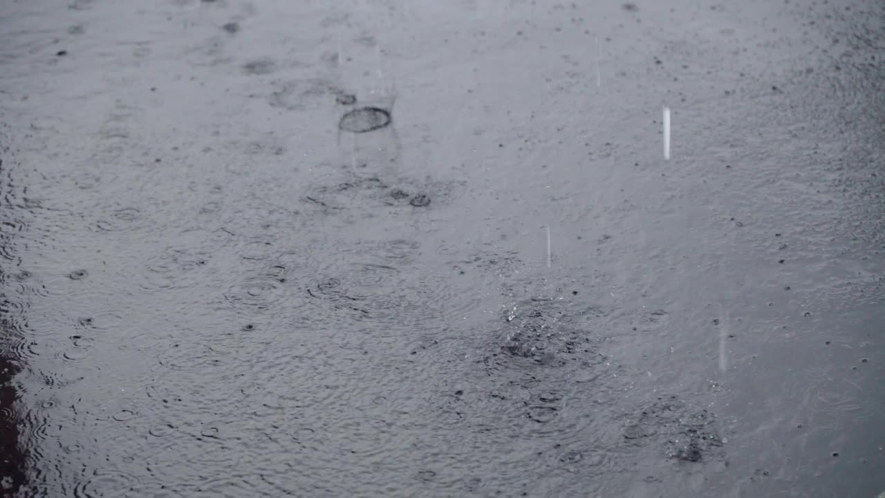 当雨滴落下时，水坑上的雨水在水面上泛起涟漪。有选择性的重点视频素材