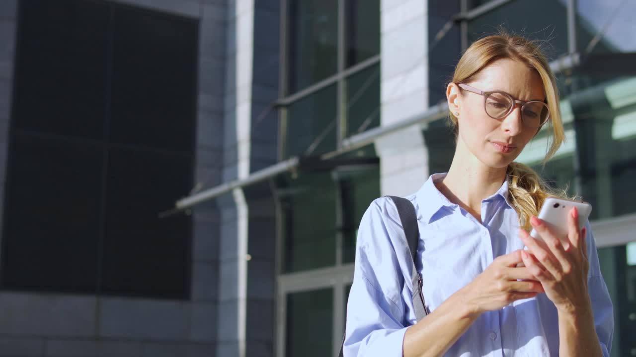 穿着休闲衬衫、一头金发的集中女性表情严肃地阅读智能手机上的信息，接收坏消息或重要消息，思考信息，思考下一步的行动视频素材