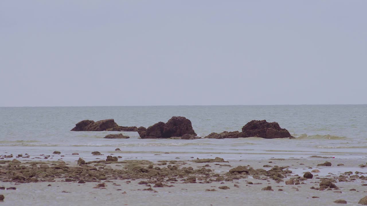 多岩石的海滩和海浪撞击岩石或海石，形成浪花的海景。Endau、马来西亚视频素材