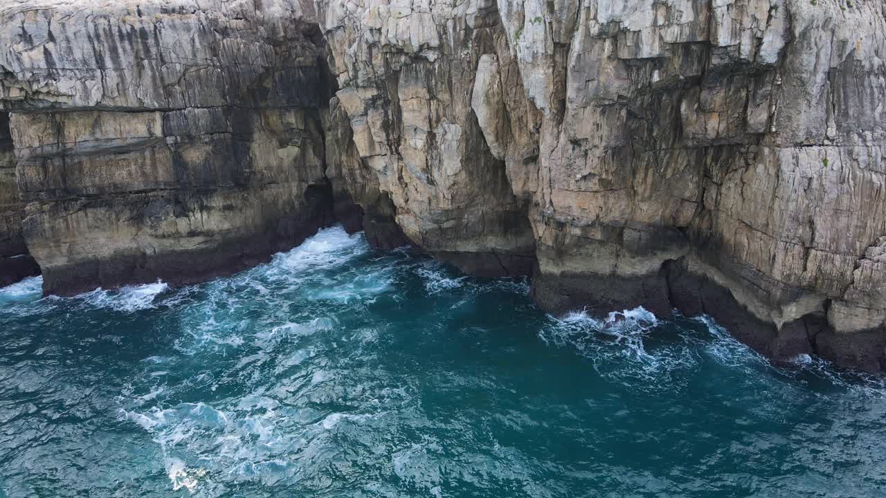 鸟瞰图的波浪打破岩石在蓝色的海洋。鸟瞰图的海浪撞击岩石悬崖。高质量4k素材视频素材