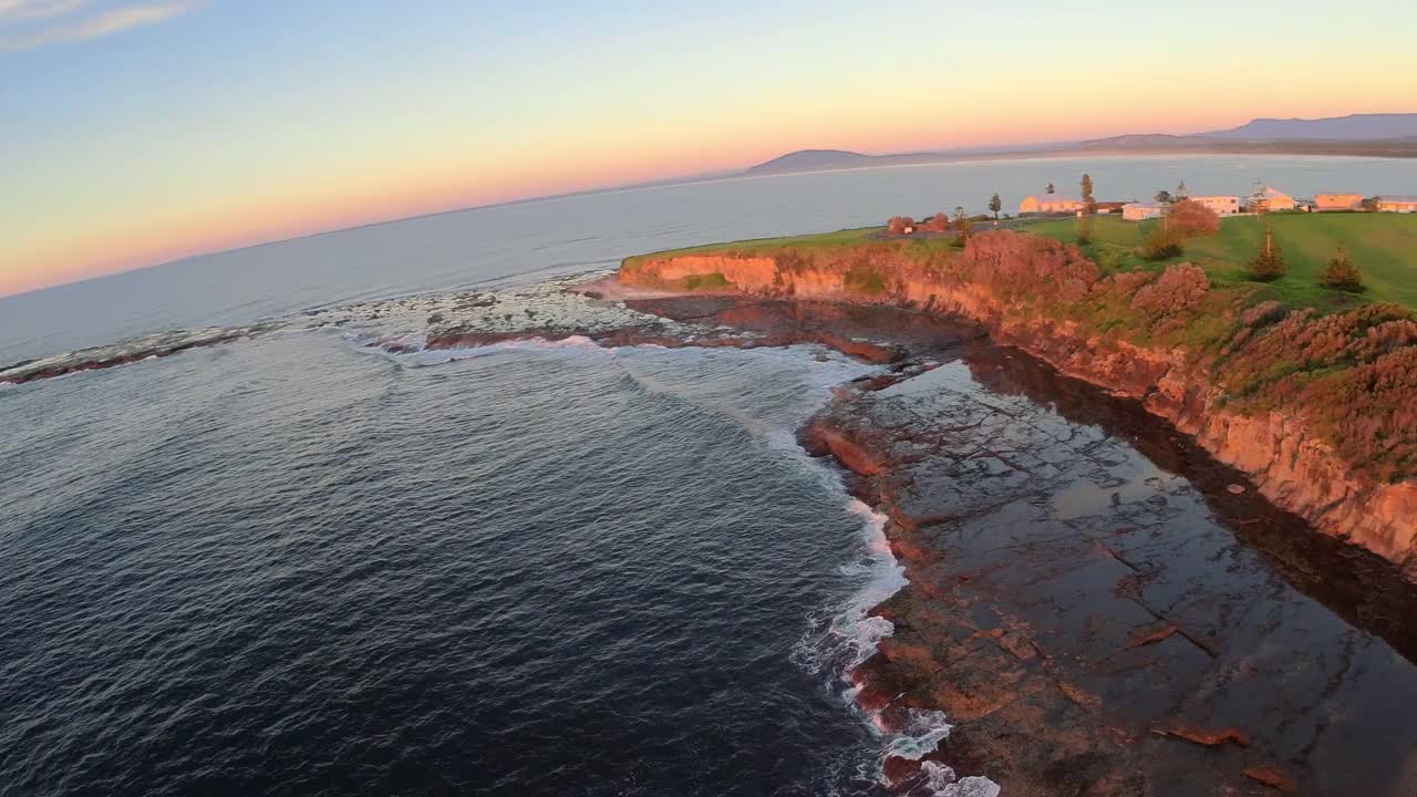 澳大利亚新南威尔士州东海岸，在日出时低空俯瞰海浪撞击岩壁的景象。视频素材