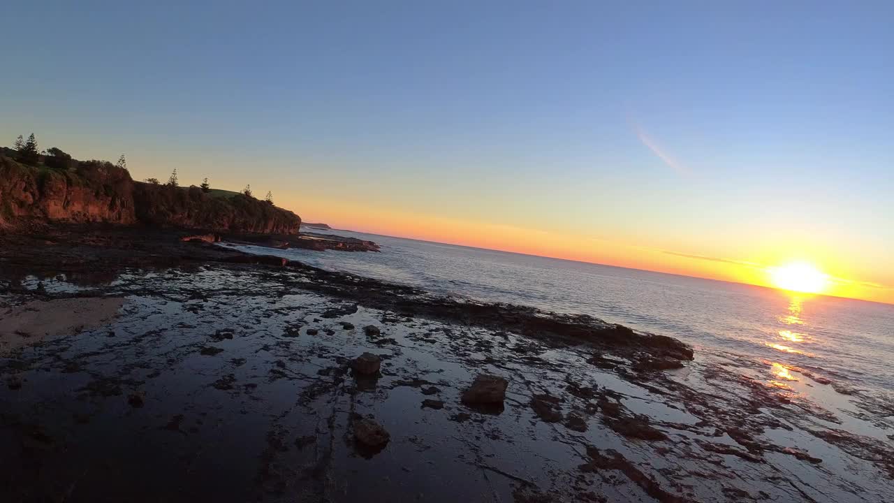 在澳大利亚新南威尔士州东海岸，在日出时快速低飞的海岸岩礁鸟瞰图。视频素材