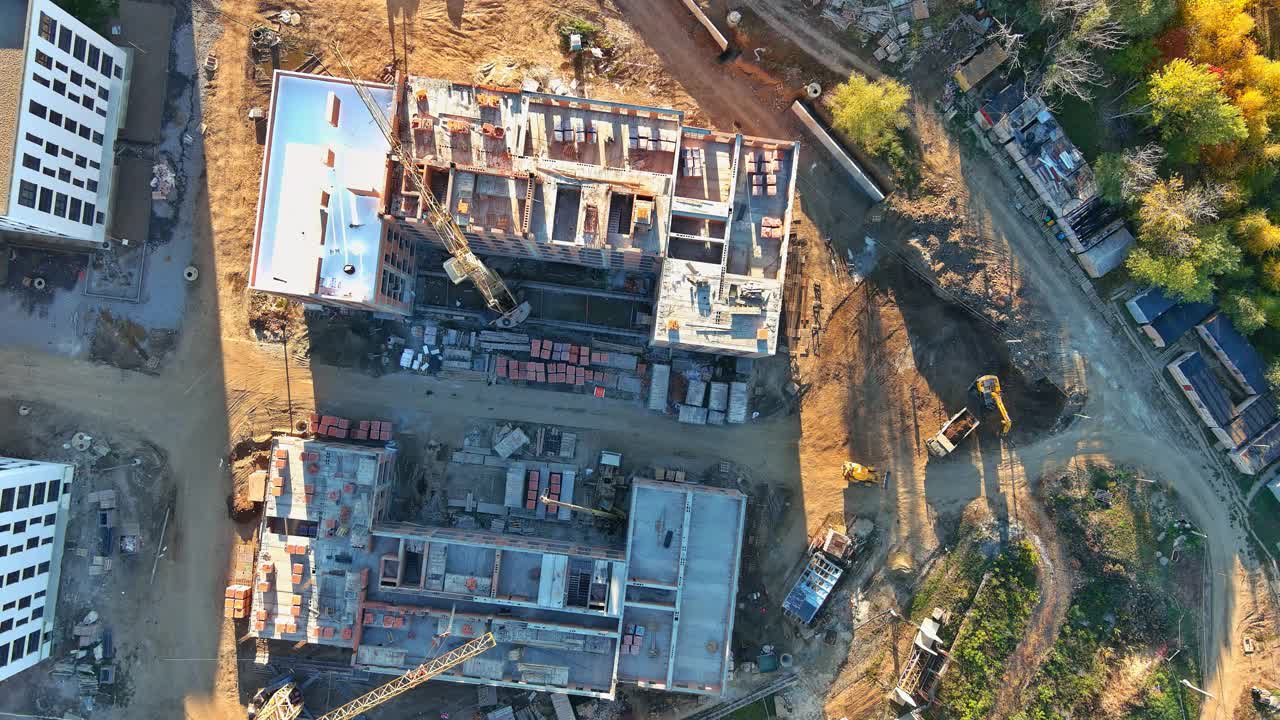 在用几台建筑塔式起重机建造公寓楼时，建筑工地的全景俯视图视频素材