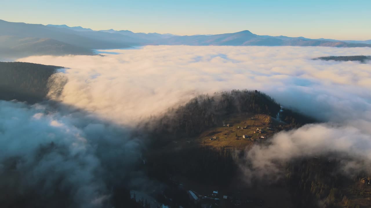 鸟瞰充满活力的景观，雾蒙蒙的云朵覆盖着小山和散落的小村舍。视频素材