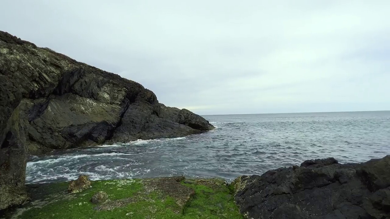 一个美丽的自然景象，小波浪的岩石海岸在潮水退去的海岸。视频素材