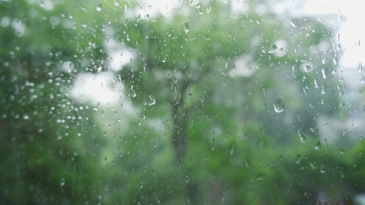 雨和水珠落在玻璃在暴雨期间，关闭。窗外的雨天。视频素材