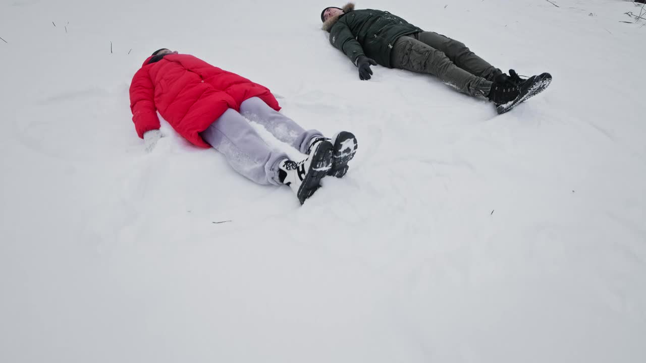 一家人在冬天玩得很开心。年轻的夫妇做雪天使。视频素材