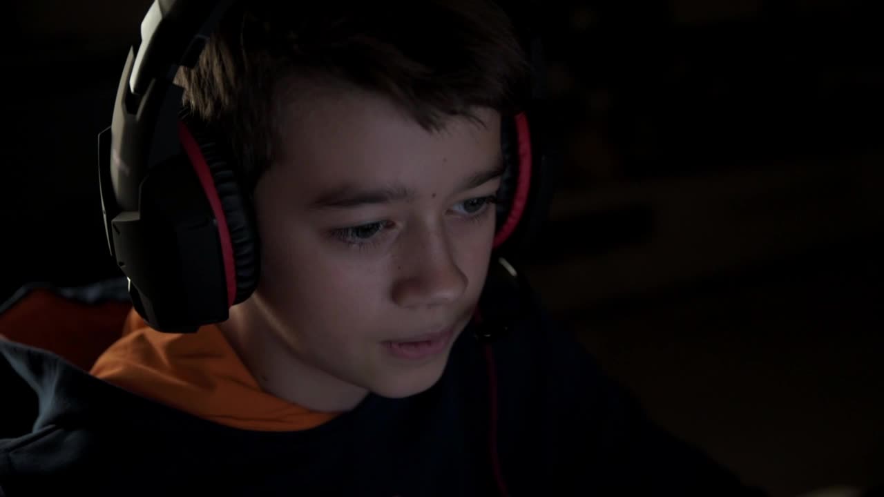 男孩戴着耳机玩网络游戏视频素材
