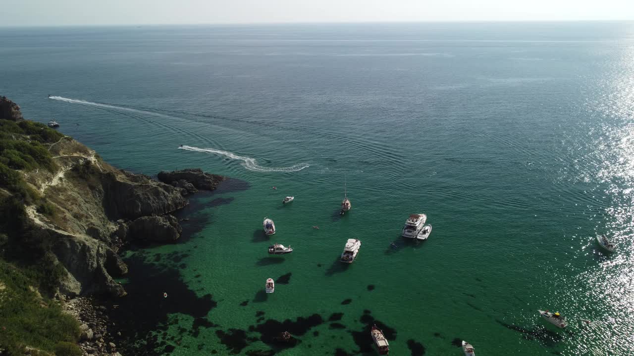 鸟瞰海景与清澈蔚蓝的大海和岩石海岸。游艇在岩石背景下美丽的泻湖上。夏季旅游和度假的理想目的地的概念视频素材