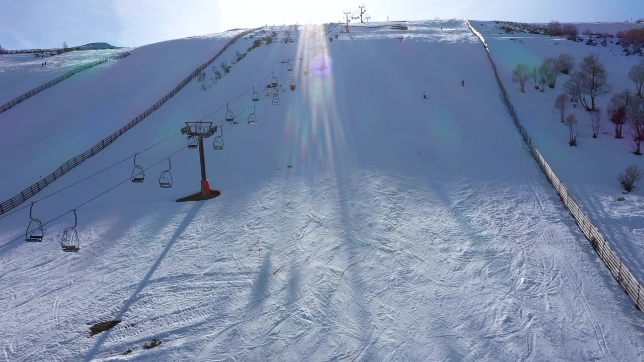 在西班牙里昂，一个阳光明媚的日子里，无人机瞄准电梯，人们在Leitariegos滑雪场的斜坡上滑雪视频素材