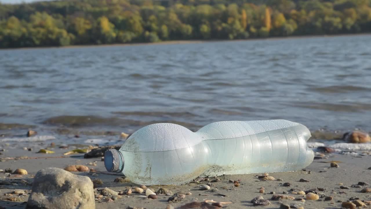 把垃圾洒在大城市的海滩上。清空用过的脏塑料瓶。肮脏的海边沙滩。环境污染。生态问题。背景是移动的波浪视频素材