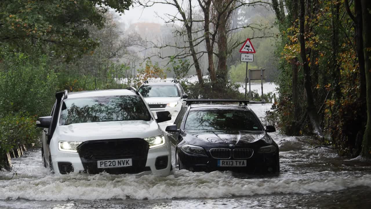 在英国湖区安布尔赛德，一辆宝马被遗弃在被洪水淹没的道路上，暴雨导致罗赛河决堤。视频素材