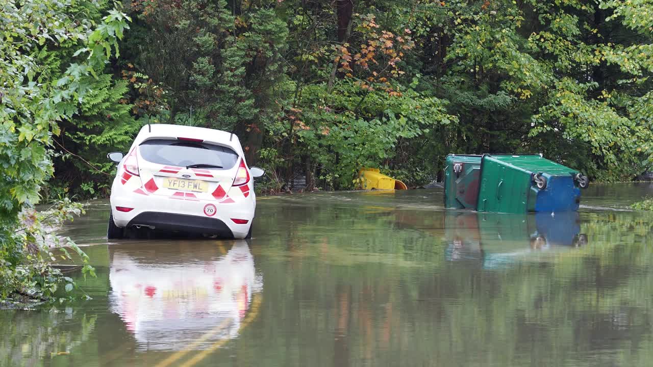 在英国湖区安布尔赛德的一条被洪水淹没的道路上，暴雨导致罗赛河决堤，有轮子的垃圾桶被洪水冲到道路上。视频素材