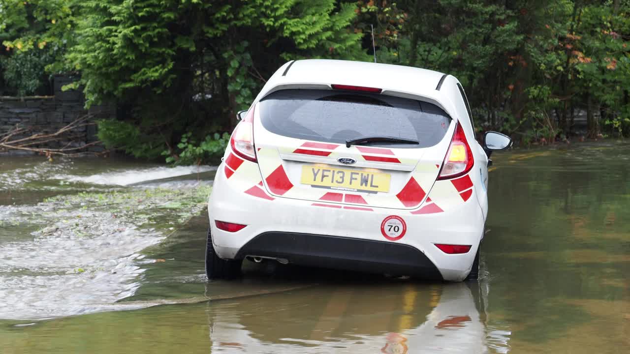 在英国湖区安布尔赛德的一条被洪水淹没的道路上，暴雨导致罗赛河决堤，有轮子的垃圾桶被洪水冲到道路上。视频素材