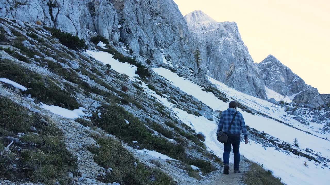 成年男子在雪山步道上徒步的慢动作跟踪镜头视频素材