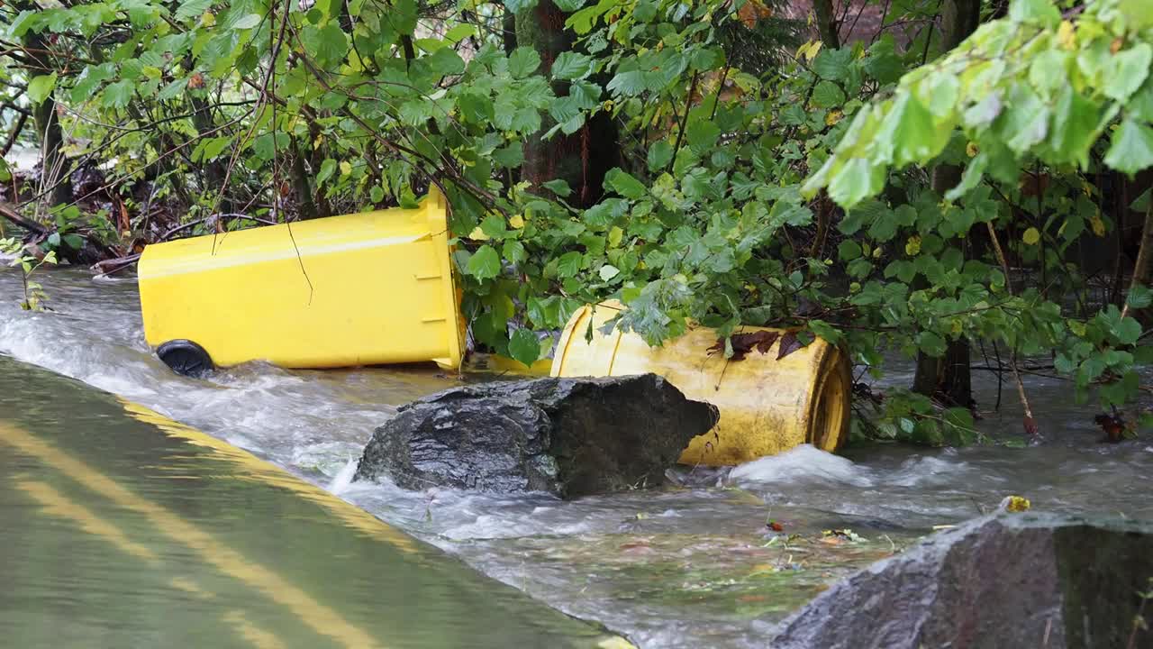 在英国湖区安布尔赛德的一条被洪水淹没的道路上，暴雨导致罗赛河决堤，有轮子的垃圾桶被洪水冲到道路上。视频素材