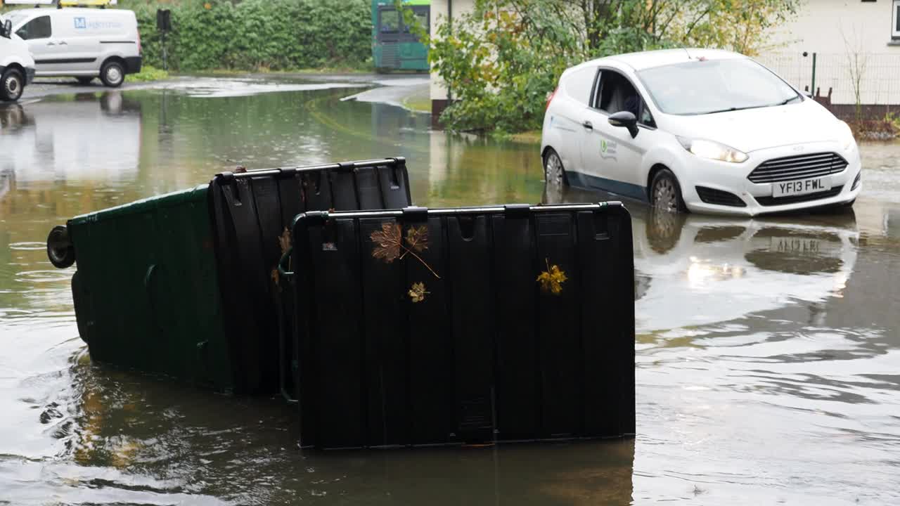 在英国湖区安布尔赛德的一条被洪水淹没的道路上，暴雨导致罗赛河决堤，有轮子的垃圾桶被洪水冲到道路上。视频素材