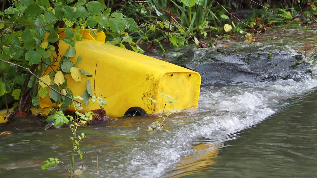 在英国湖区安布尔赛德的一条被洪水淹没的道路上，暴雨导致罗赛河决堤，有轮子的垃圾桶被洪水冲到道路上。视频素材