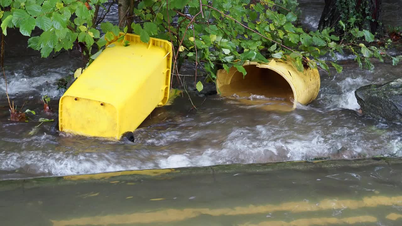 在英国湖区安布尔赛德的一条被洪水淹没的道路上，暴雨导致罗赛河决堤，有轮子的垃圾桶被洪水冲到道路上。视频素材