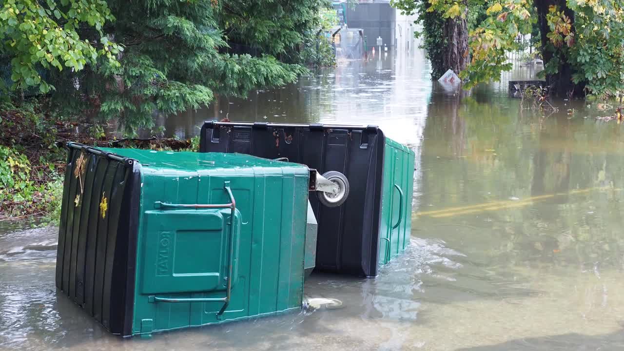 在英国湖区安布尔赛德的一条被洪水淹没的道路上，暴雨导致罗赛河决堤，有轮子的垃圾桶被洪水冲到道路上。视频素材