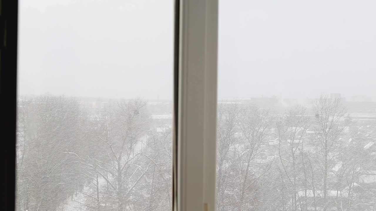 冬天从房子的窗户看到的街道。暴风雪，霜冻的天气，雪花飘落。背景视频素材