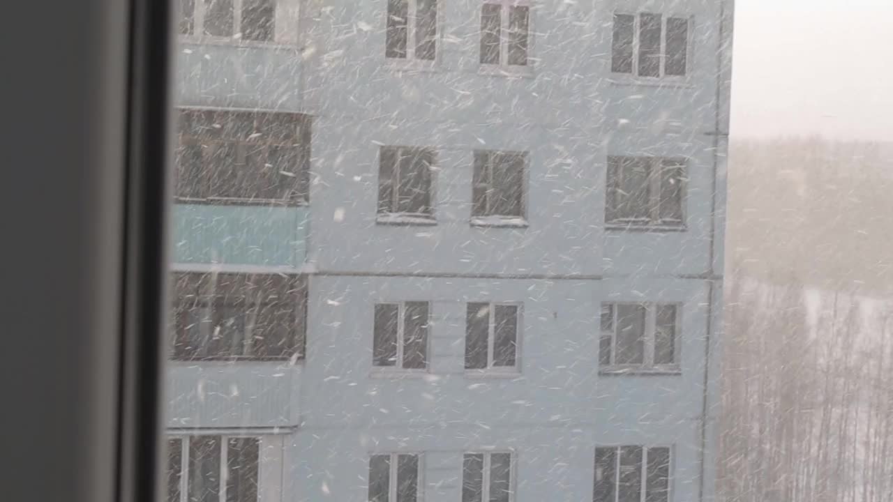 冬天从房子的窗户看到的街道。暴风雪，霜冻的天气，雪花飘落。背景视频素材