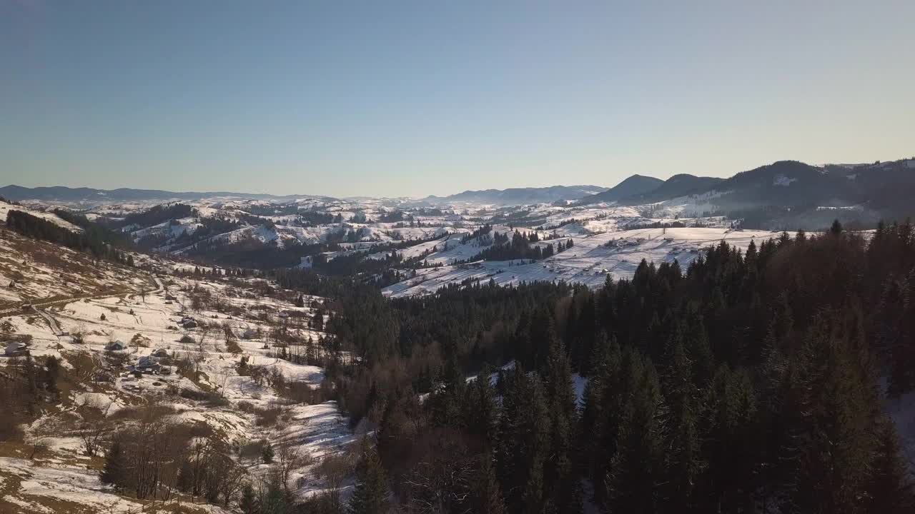 鸟瞰图小村庄与散落的房屋在冬季积雪覆盖的小山和裸露的喀尔巴阡山脉在乌克兰视频素材