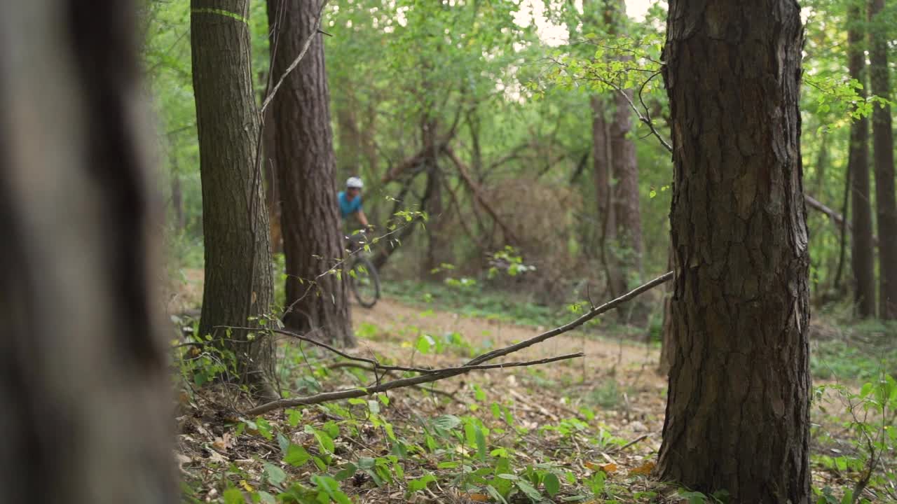 年轻的山地自行车手在森林里的一条小路上爬行视频素材