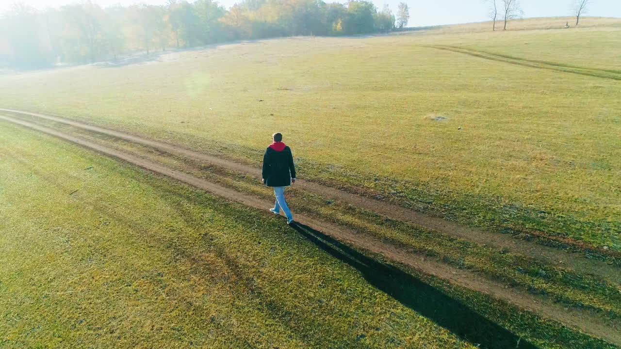 一名男子在秋天走在路上的航拍视频视频素材