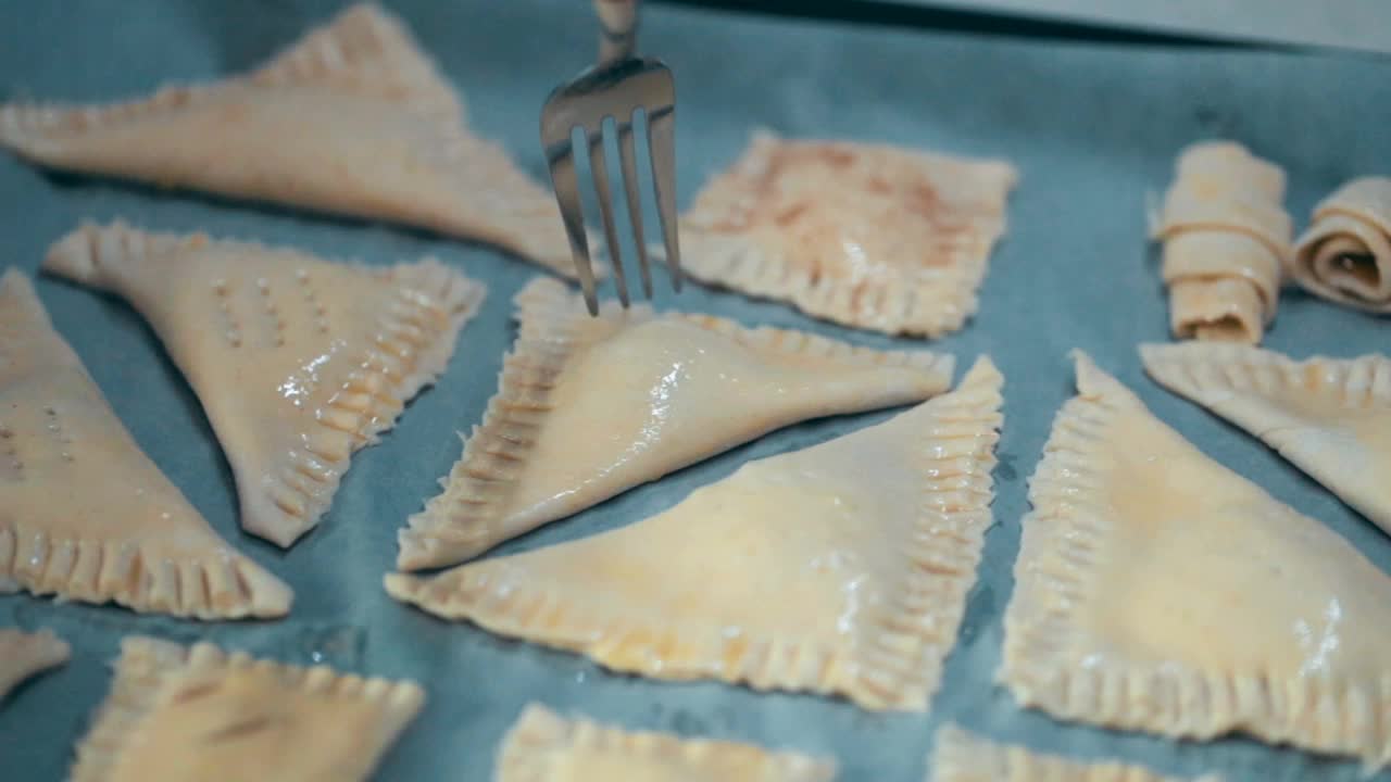 Сook在把生酥皮馅饼放进烤箱之前，先用叉子装饰一下。烹饪烘焙的过程视频素材