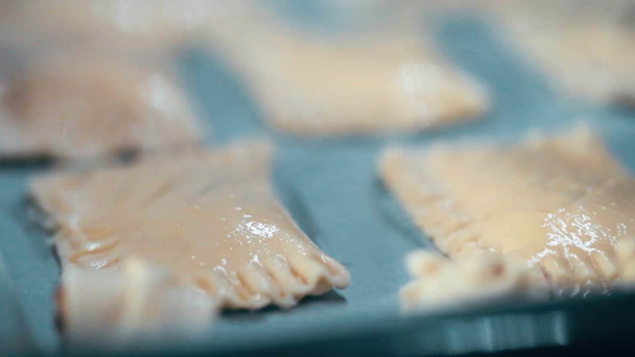 在送进烤箱之前，库克在生的酥皮派上撒上芝麻。烹饪烘焙的过程视频素材