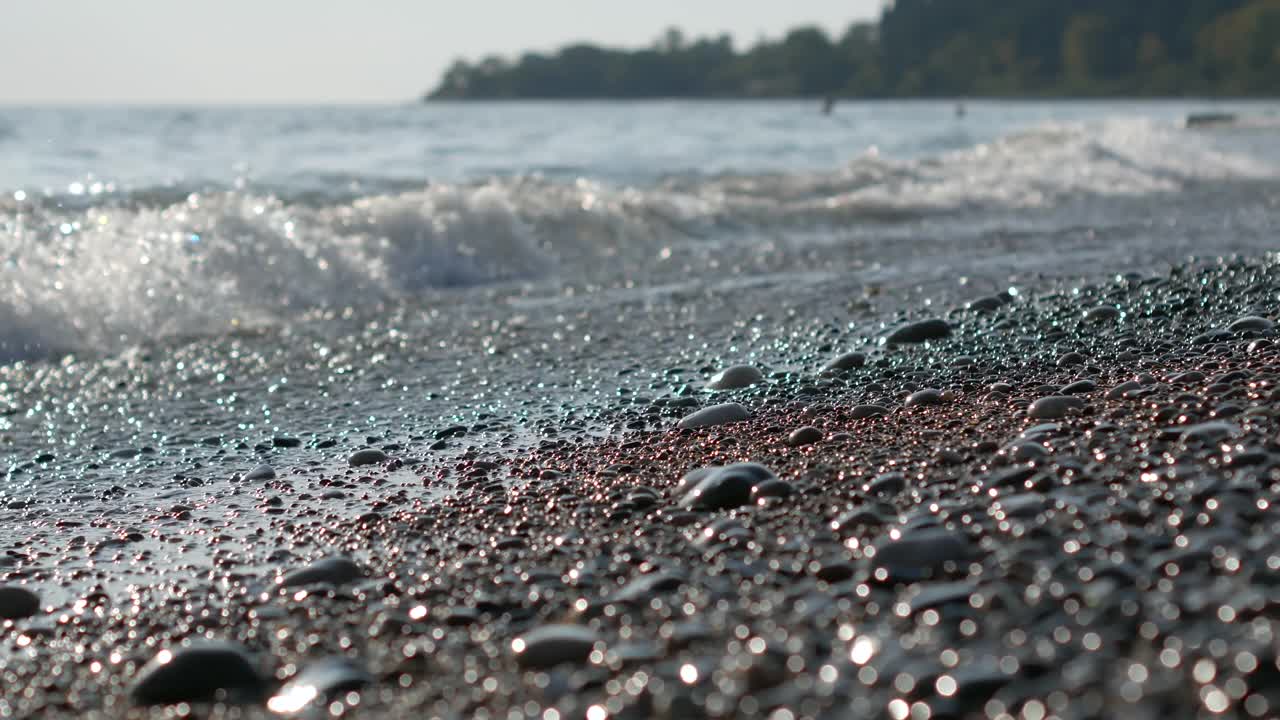 海水在海浪中冒着泡沫，海滩上布满了鹅卵石视频素材