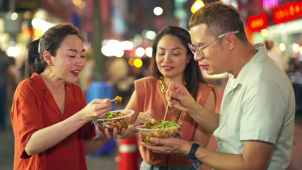 4K泰国曼谷街头夜市，一群亚洲人朋友一起吃辣烤鱿鱼视频素材