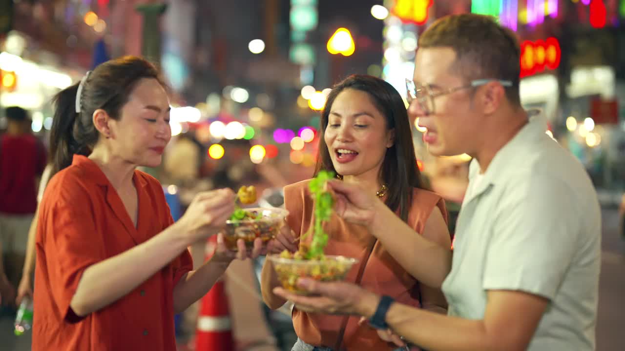 4K泰国曼谷街头夜市，一群亚洲人朋友一起吃辣烤鱿鱼视频素材