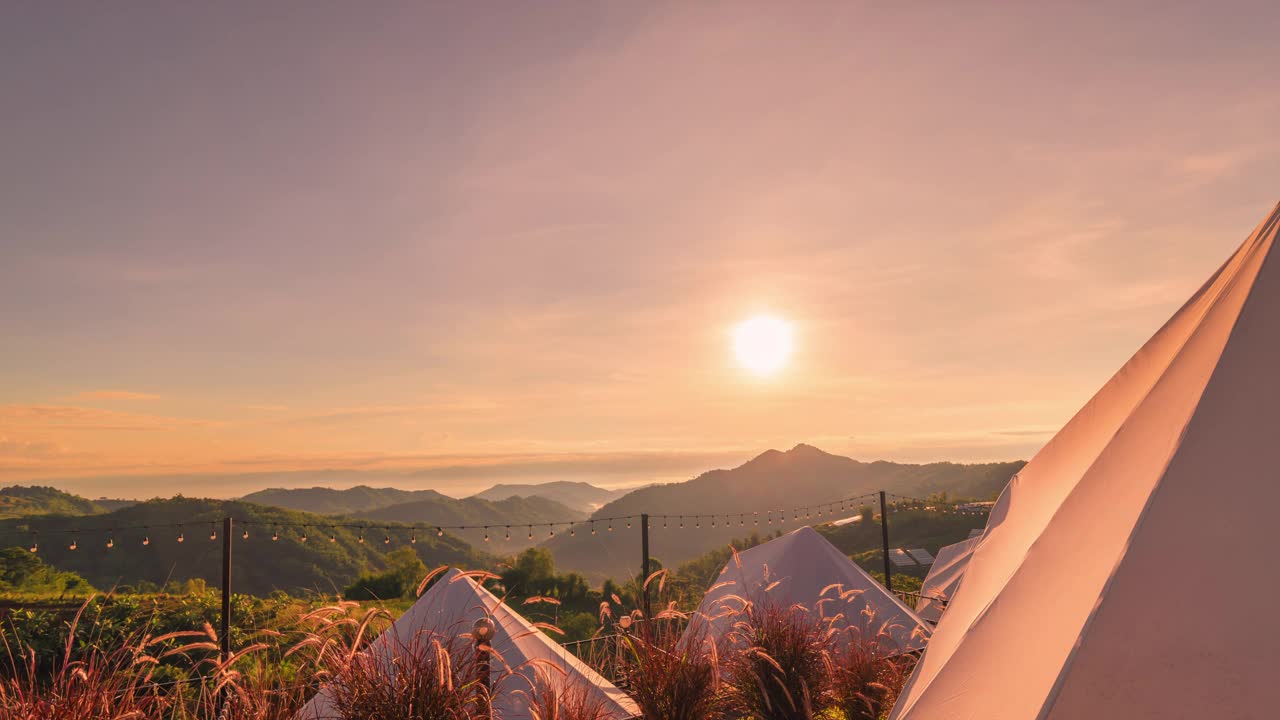 时光流逝，日落时分在松树林下露营，
红色的夕阳和山脉的背景，夏季的风景。视频素材