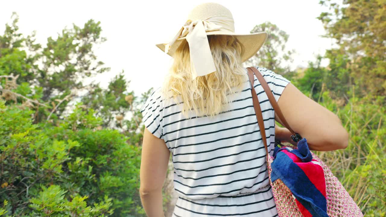 意大利撒丁岛，一个金发女人在夏日的海滩上散步。视频素材