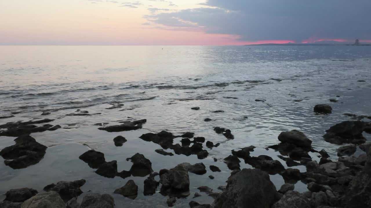 塞浦路斯阿伊纳帕港附近的岩石海滩上，日落时的柔和海浪视频素材