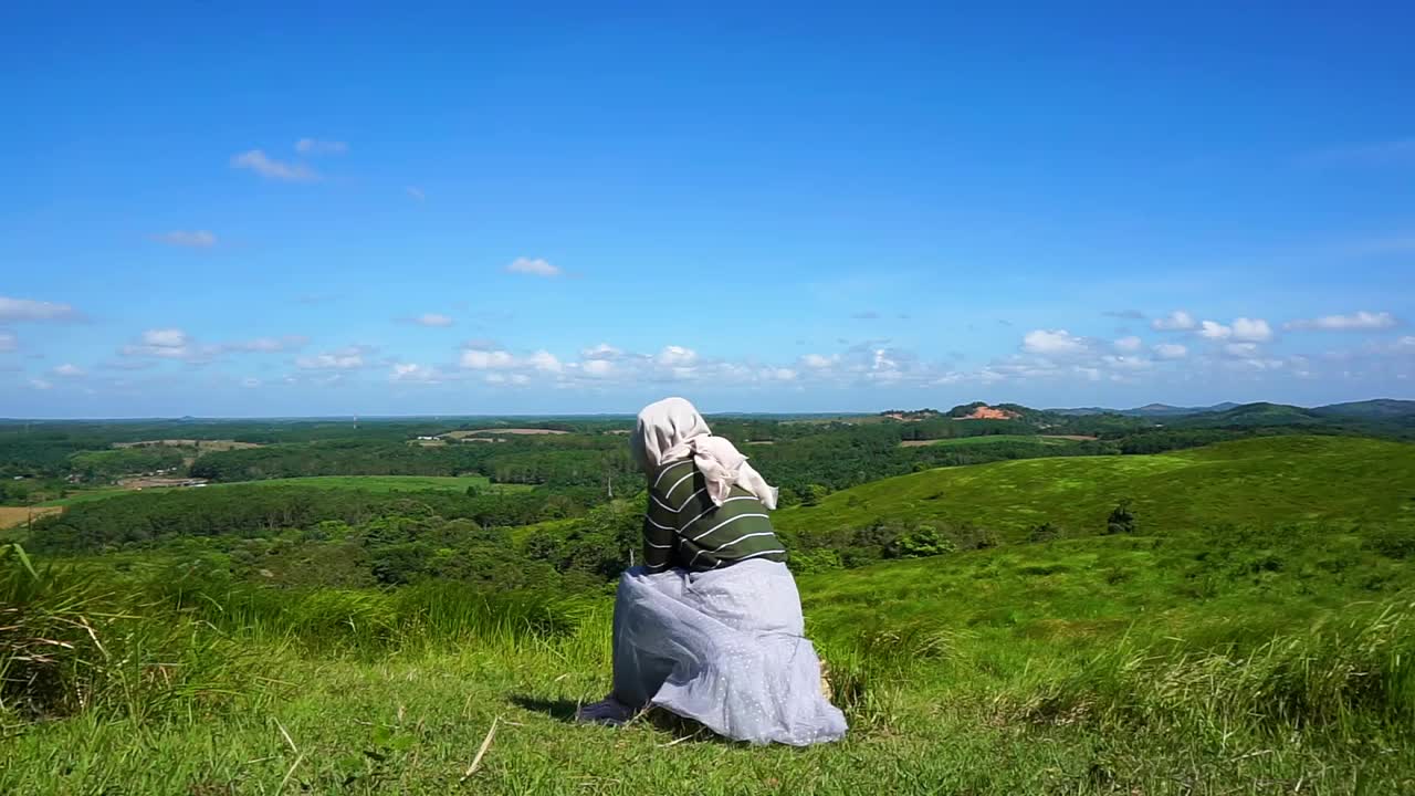 年轻的女人坐在山顶上，自由，放松视频素材