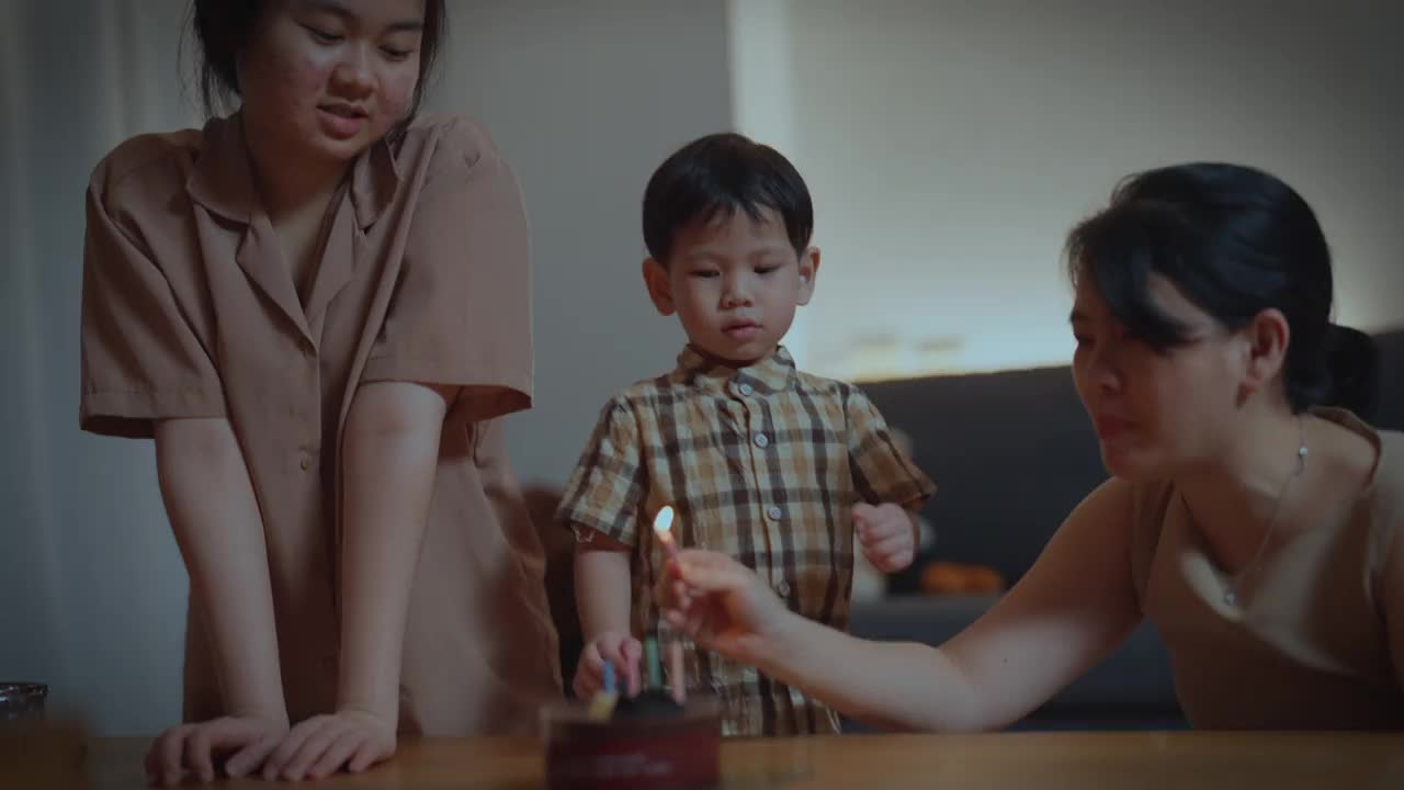 亚洲泰国家庭在客厅点燃生日蜡烛庆祝男孩的生日视频素材