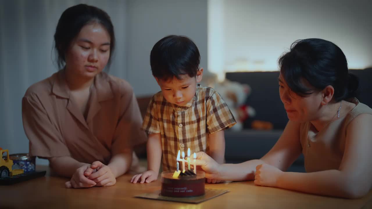 亚洲泰国家庭在客厅点燃生日蜡烛庆祝男孩的生日视频素材