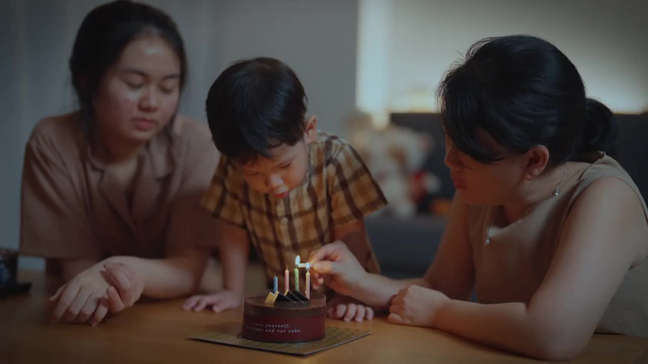 亚洲泰国家庭在客厅点燃生日蜡烛庆祝男孩的生日视频素材