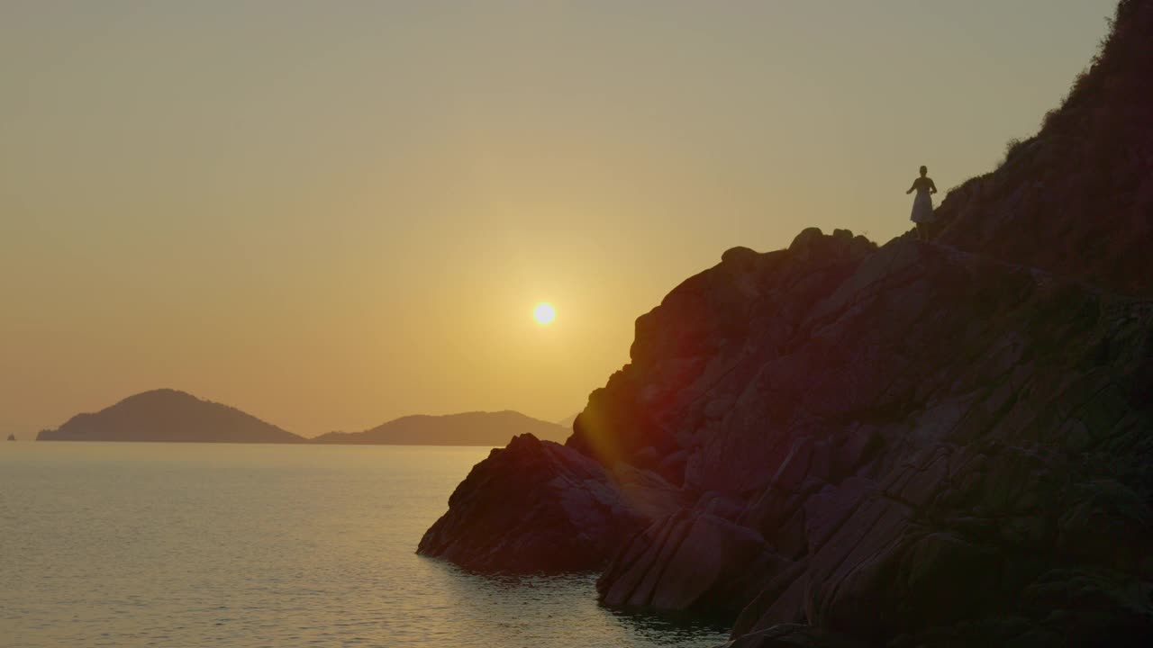 一个女人在日落时沿着海岸冥想，厄尔巴岛。视频素材