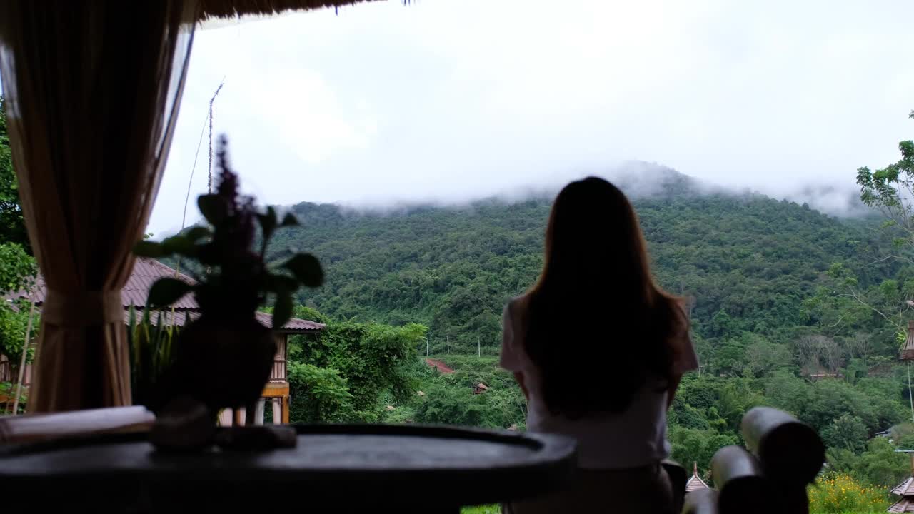 一个女人在雾天坐着，放松地看着美丽的山景视频素材