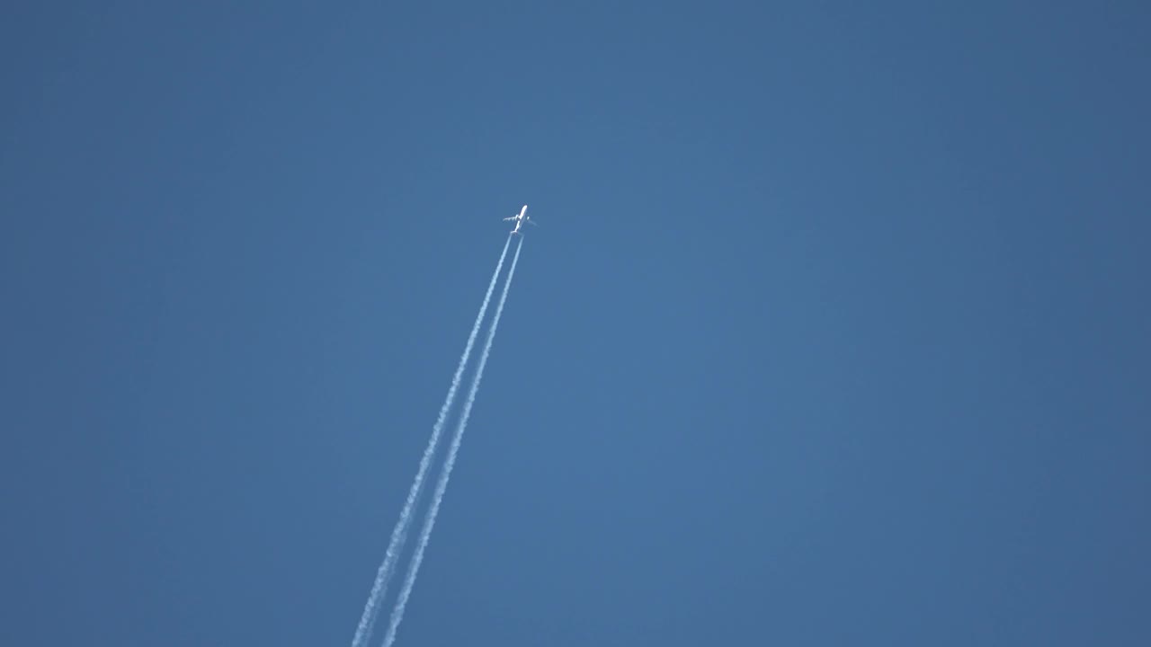 喷气式客机在高空飞行，在湛蓝的天空中留下了尾迹。视频素材